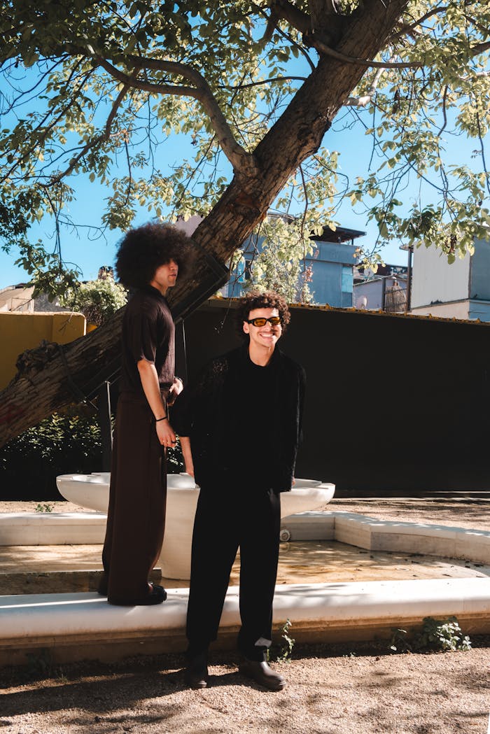 Two people standing next to each other in front of a tree